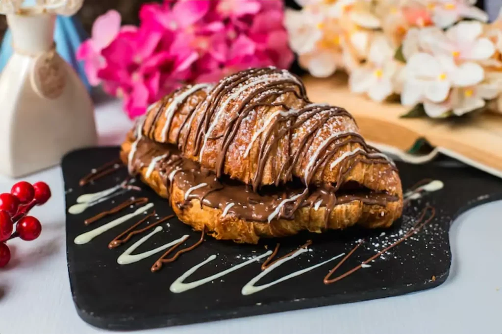 Side view of croissant decorated with chocolate on a wooden board