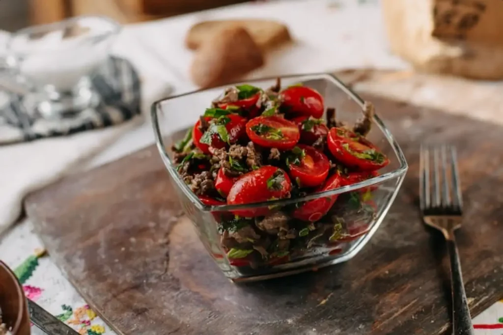 sliced red tomatoes along with brown beans greens on brown wood rustic desk
