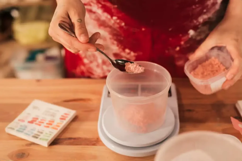 Color powder in plastic bowl on measuring scale over the wooden desk